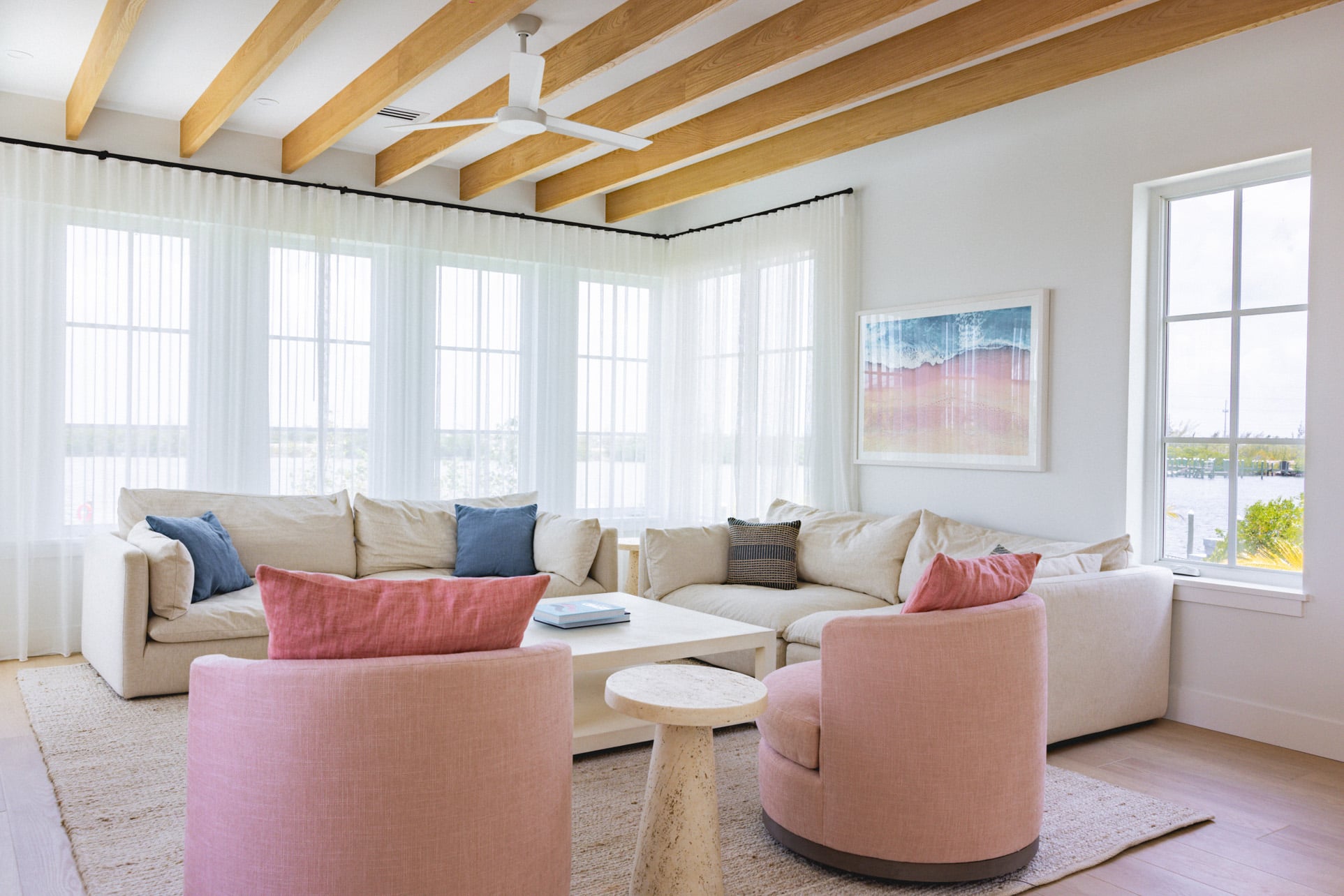 A living room interior of a villa with pink chairs and accent pillows