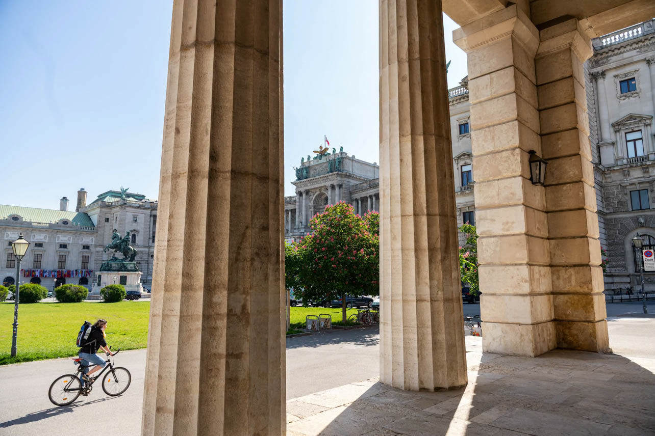 An exterior shot of a woman riding her bike outside the Austrian National Library