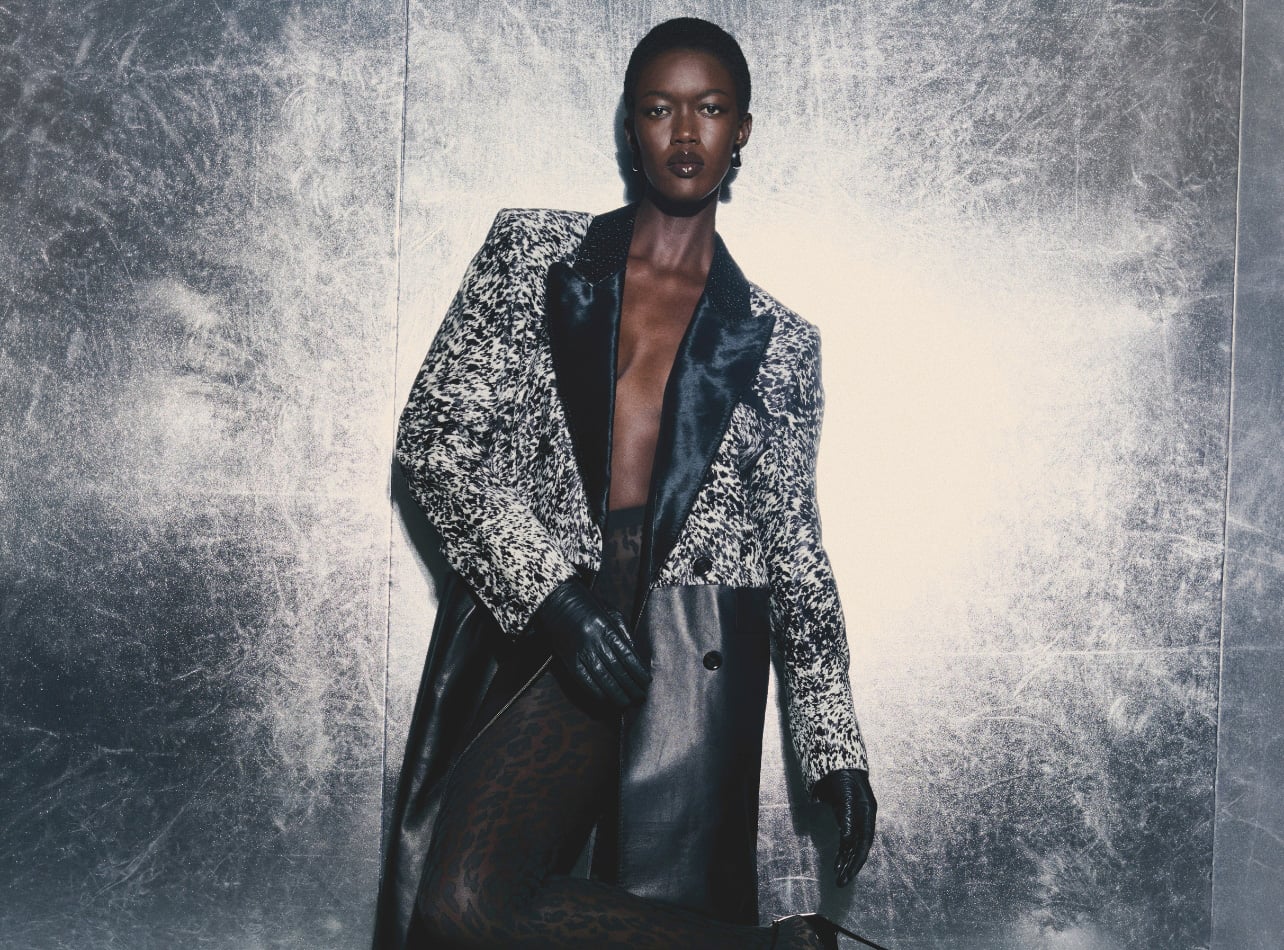 A fashion portrait of a woman wearing a Tom Ford Jacket against a metallic wall