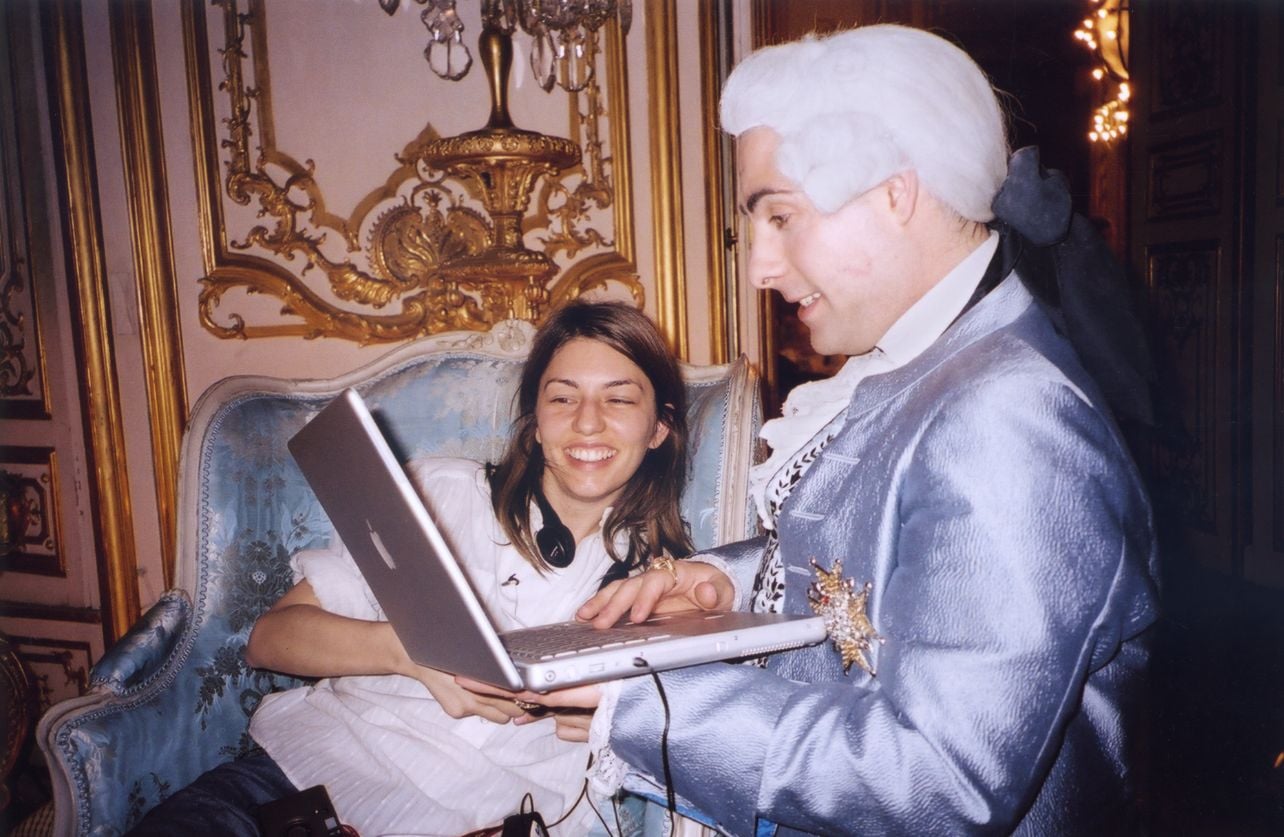 A behind the scenes shot from the making of Making Marie Antoinette with an actor holding a laptop